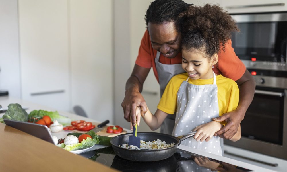 Caring Black Dad Teaching His Preteen Daughter Cooking Food At Home, Happy African American Family Father And Female Child Preparing Lunch Together In Kitchen, Making Meal In Pan, Copy Space