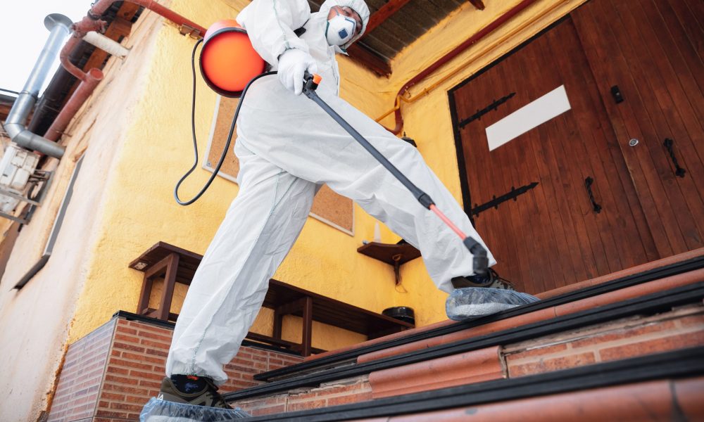 Coronavirus Pandemic. A disinfector in a protective suit and mask sprays disinfectants in house or office. Protection against COVID-19 disease. Prevention of spreding pneumonia virus with surfaces.